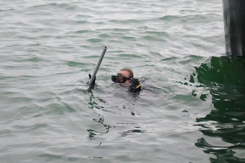 Navy diver inspects the hull of a Navy tugboat, at Guantanamo